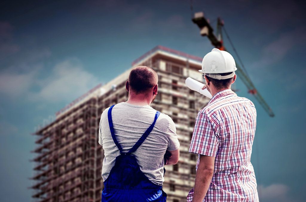 Trabajadores con casco de seguridad frente a una obra en construcción